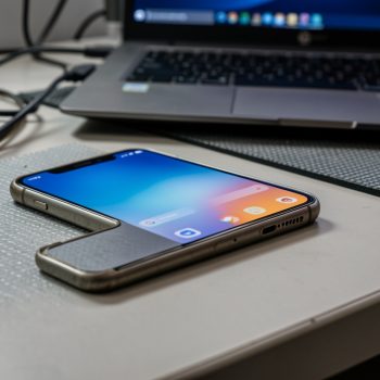 Ancien smartphone posé sur un bureau technique, ambiance cybersécurité sobre, écran affichant une interface système personnalisée sans texte lisible.