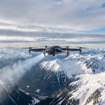 Drone VTOL d’ensemencement survolant des montagnes enneigées sous des nuages froids, avec une visualisation discrète de données météorologiques abstraites.